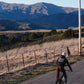 Person riding a bicycle on a road with mountains in the background