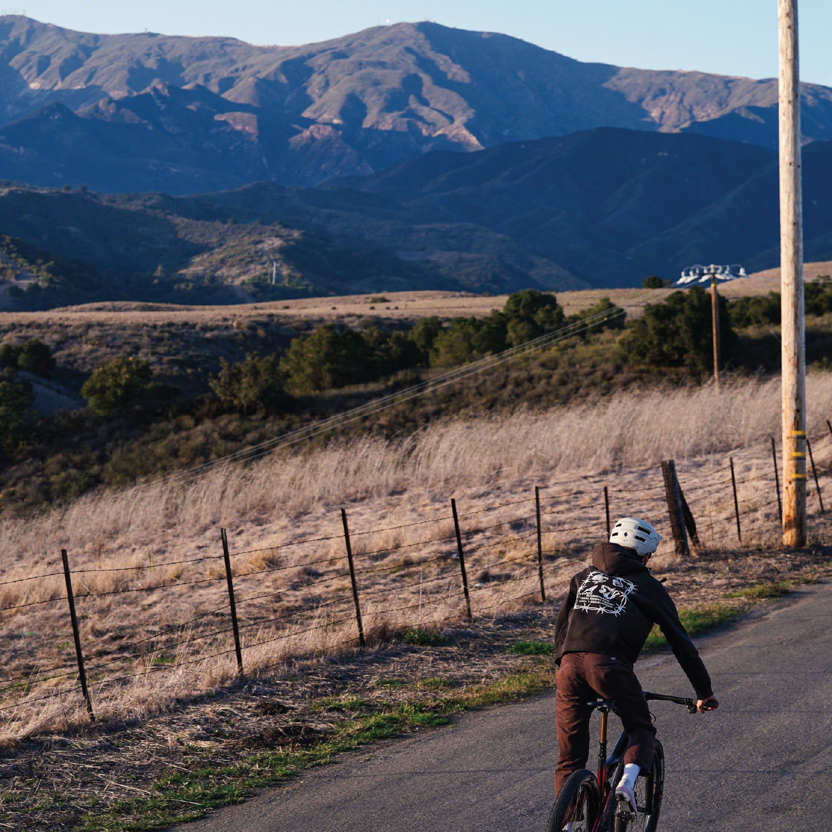 Person riding a bicycle on a road with mountains in the background